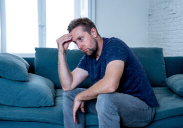 Unhappy depressed caucasian male crying in living room couch feeling desperate and lonely isolated at home. In stressed from work, unemployment, anxiety, heartbroken and depression concept